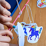 Student balancing paper mobile elements on a straw
