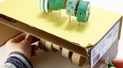  Sideview of the automaton with the axle just sticking out of a side panel.  A bead is being glued on.   