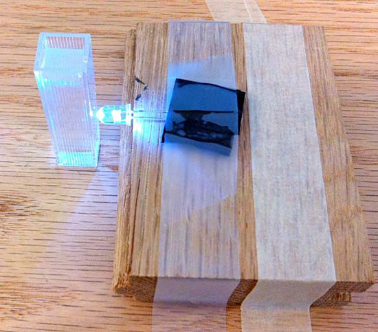 A cuvetter filled with clear water placed directly in-front of a lit LED bulb