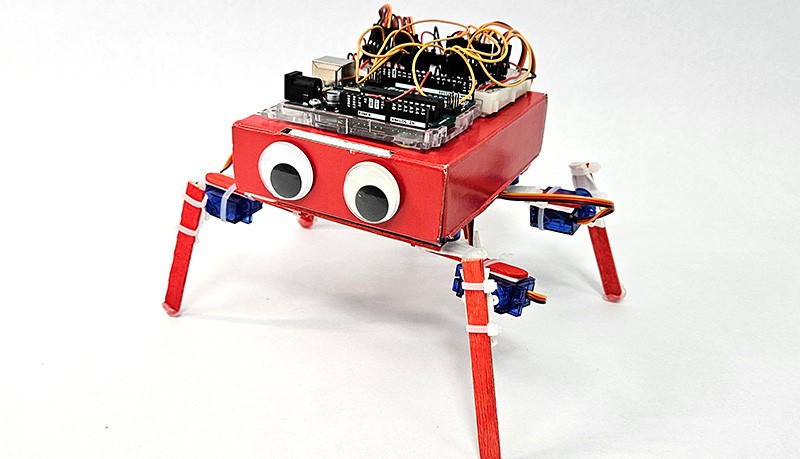 An Arduino walking robot with a cardboard box body and popsicle stick legs