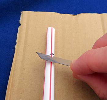 Notches are cut in a plastic straw using a razor blade