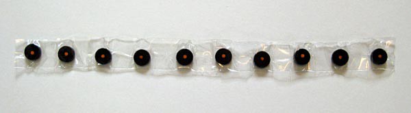 Ten circular magnets are lined up in the same polar direction and laid on a long strip of clear tape