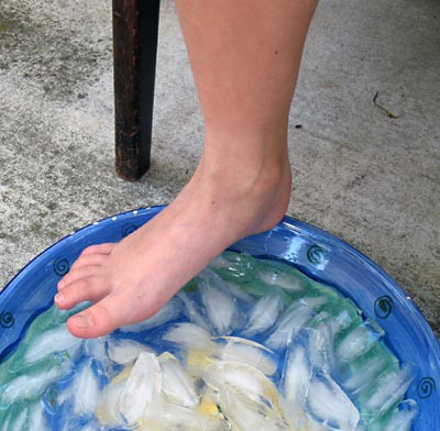 A foot hovers above a tub filled with water and ice