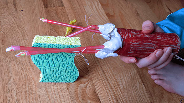 Student testing homemade robot hand to pick up household items like a sponge