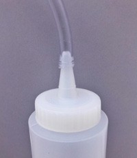 A plastic tube connects to the nozzle of a squeeze-bottle