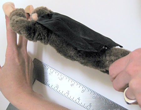 Stuffed toy monkey is held parallel to the edge of a carpenters square