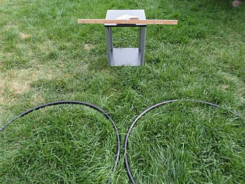 A table with a rock and yardstick on it sits in front of two hula hoops laying on the ground