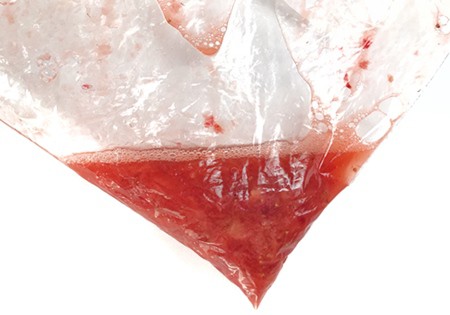 Strawberries are crushed in a plastic bag until a red liquid is formed