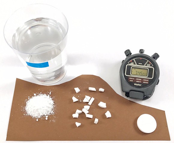 A cup of water, a timer, and different forms of alka-seltzer tablet