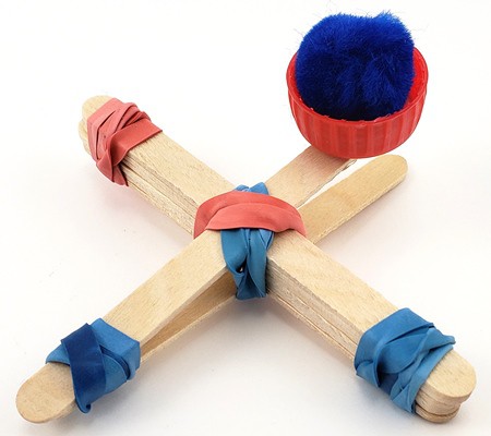 Catapult built with popsicle sticks, rubber bands, and a plastic bottle cap, holding a cotton ball
