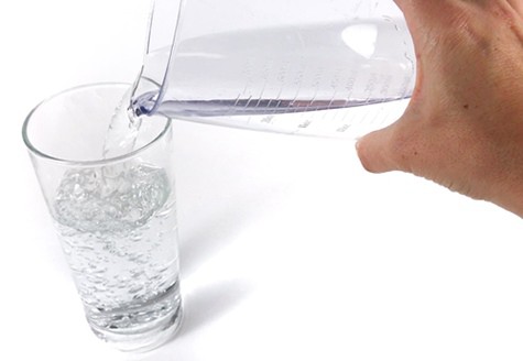 Water is poured from a pitcher into a glass.