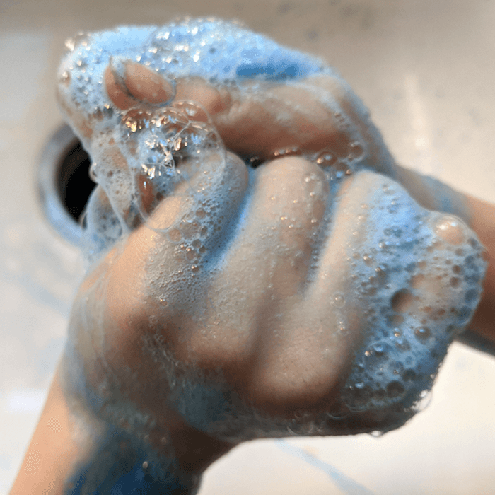 Kid washing hands with soap to try and get paint off
