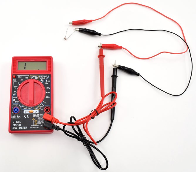 Alligator clips connect the leads of a photoresistor to the probes of a multimeter
