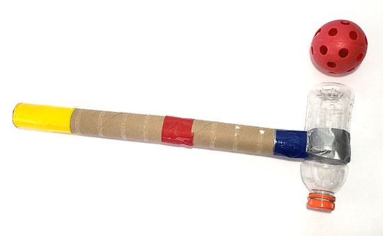 A whiffle ball next to a mallet made of a plastic bottle, tape and cardboard tubes