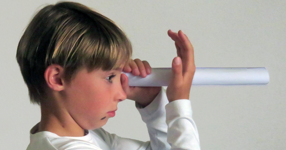 Student holding a cardboard tube to one eye and looking at the other hand for an optical illusion demonstration