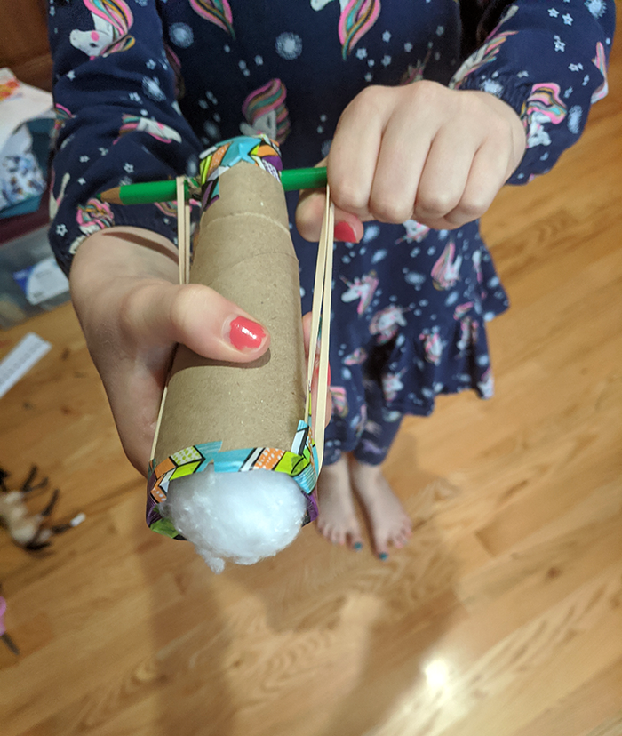 Student holding homemade cottonball launcher and aiming it