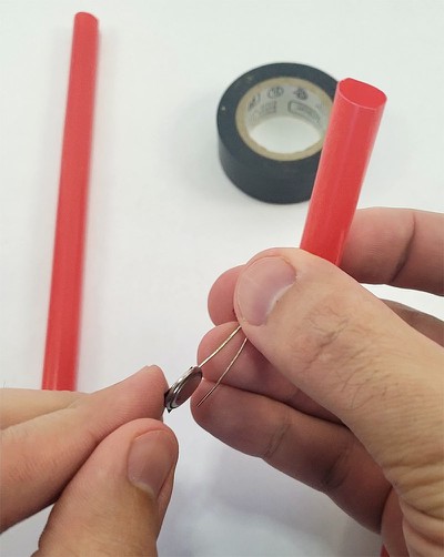 LED leg taped to one side of coin cell battery 