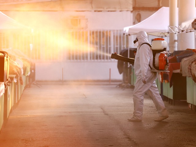 person in hazard suit decontaminating workspace