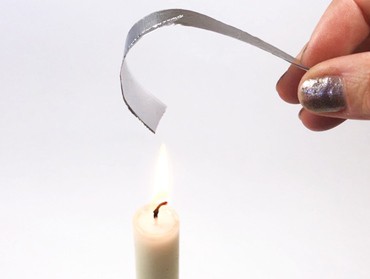 Aluminum-paper strip getting curled by holding above a candle flame.