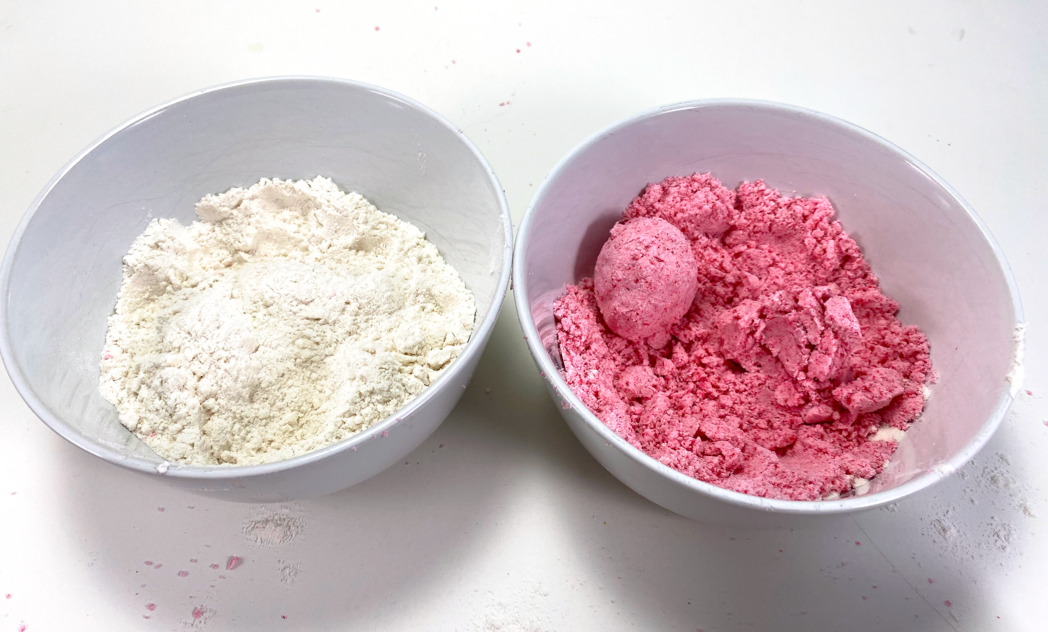 Two bowls with flour mixture, one with food coloring and oil added to make kinetic dough