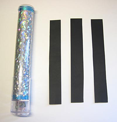 A kaleidoscope with three black strips of paper laid beside it