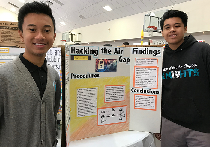 Two students standing in front of a science fair display board