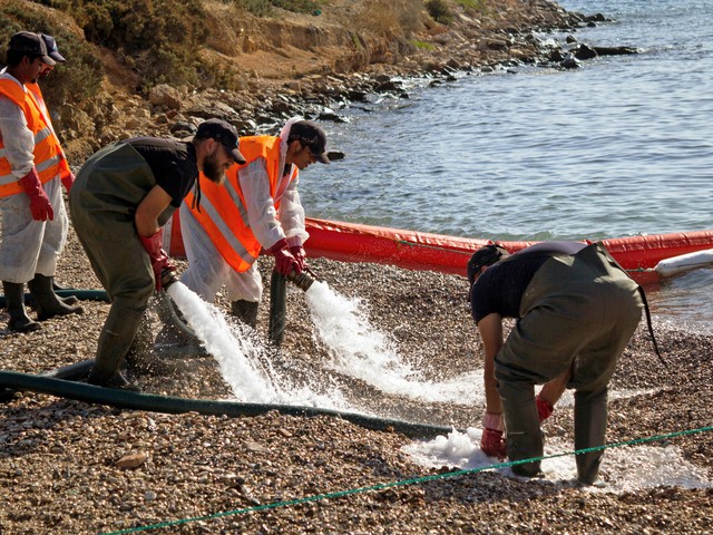 workers cleaning an oil spill on a beach