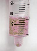 Pink sand fills a plastic syringe