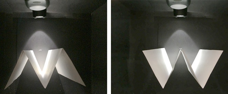  Two views of white paper folded in W shape inside a black box.    