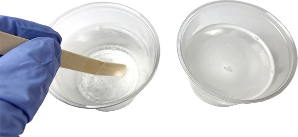 Two cups of clear solution, the left cup is mixed using a popsicle stick