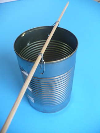 Metal wire attaches a wooden dowel across the top of a small metal can