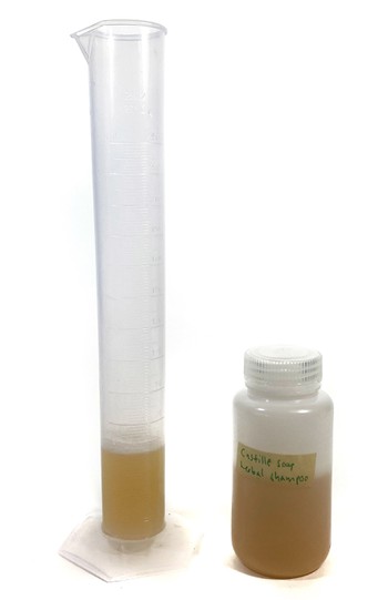 A measuring cylinder filled with 50  mL of liquid. A bottle filled with liquid stands next to the measuring cylinder.  