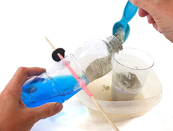 Adding soil to a plastic bottle with a tablespoon.