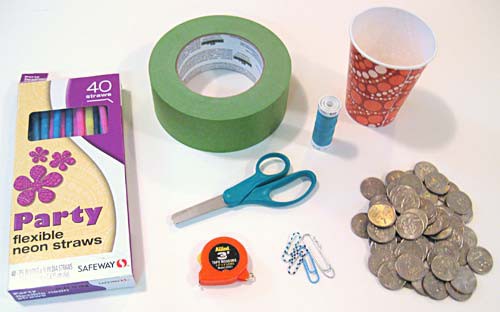 A box of straws, tape, scissors, measuring tape, four paperclips, a spool of thread, a paper cup and a pile of coins
