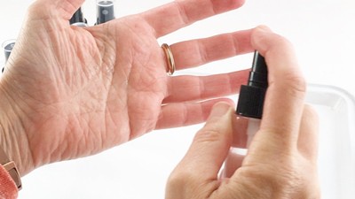 Spraying hands with a hand sanitizer.