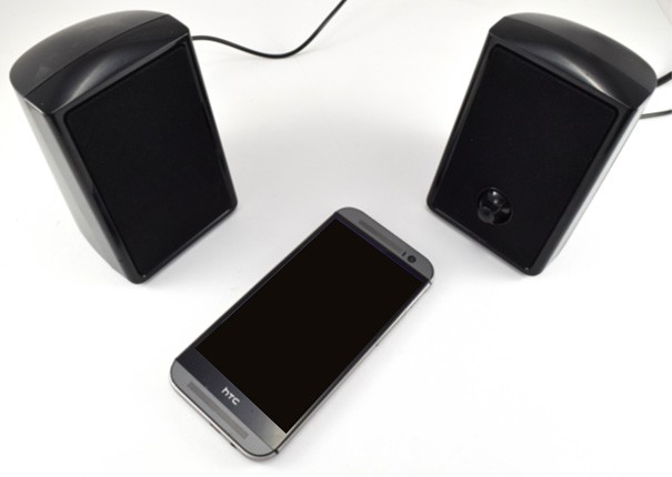 A smartphone lays between two computer speakers