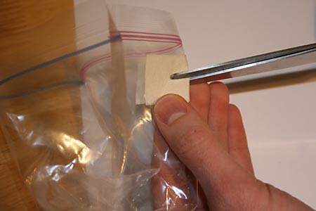 A slit is cut in the side of a plastic zip top bag over an area that has been covered by tape