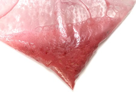 An extraction liquid is added to a bag of crushed strawberries creating a red foam above a red liquid