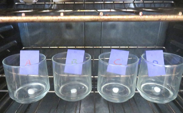 Four sections of different lip balms are placed into four cups and set on an oven rack