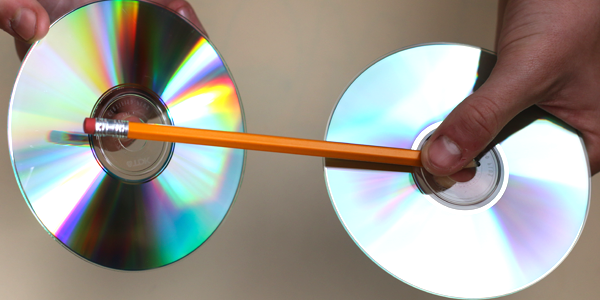 A pencil is held between two CDs