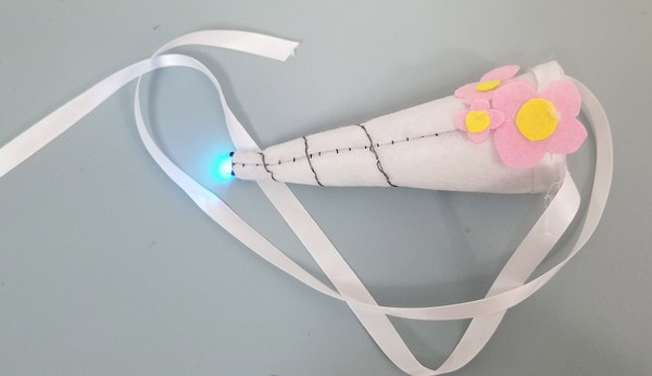 Finished unicorn horn with LED on, three flowers for decoration. 