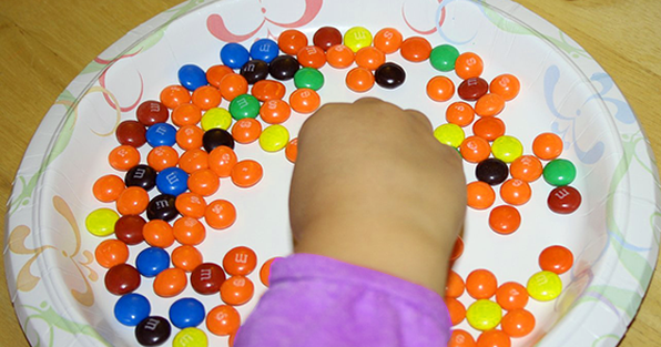 Kid hand in a try of colorful candies