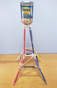 A tower made from taped-together rolls of paper with a can of beans sitting on top.  