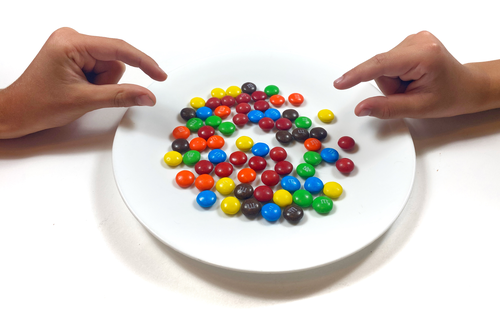 Hands prepared to grab candies from a plate for mimicry science activity