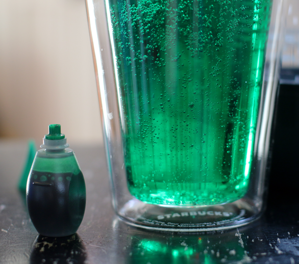 Green food coloring added to a glass of seltzer water