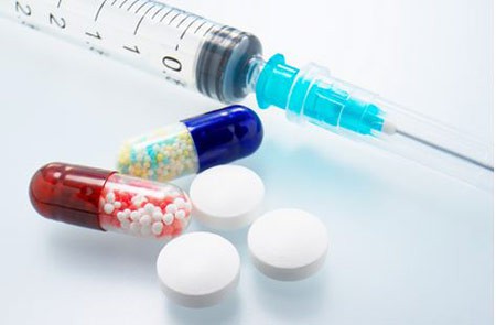 Syringe next to pill capsules and pill tablets