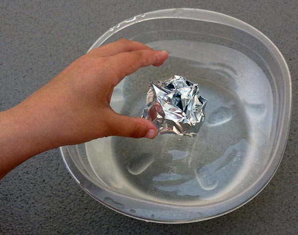 An aluminum foil ball is placed into a container filled with water