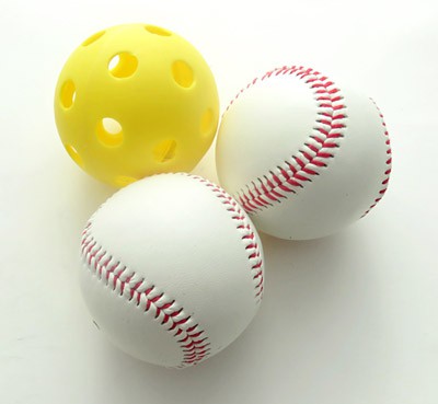 Two baseballs next to a wiffle ball