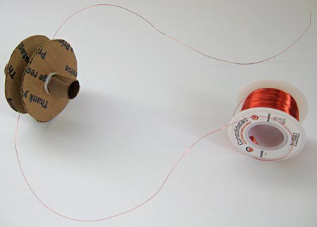 Magnet wire from a spool is wrapped around a spool made from paper and cardboard