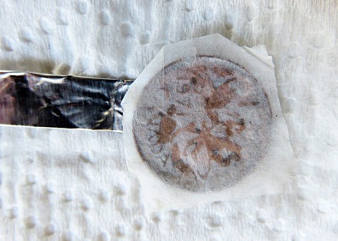 A penny is placed on the end of a strip of aluminum foil and covered with a wet paper towel square